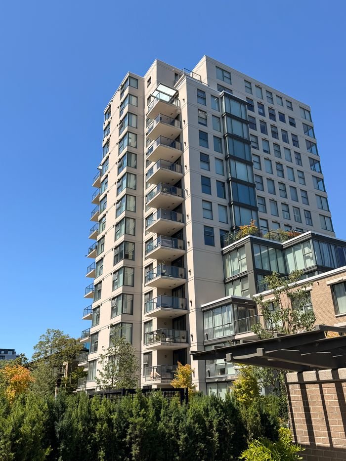 View of a modern high-rise apartment building against a clear blue sky.
